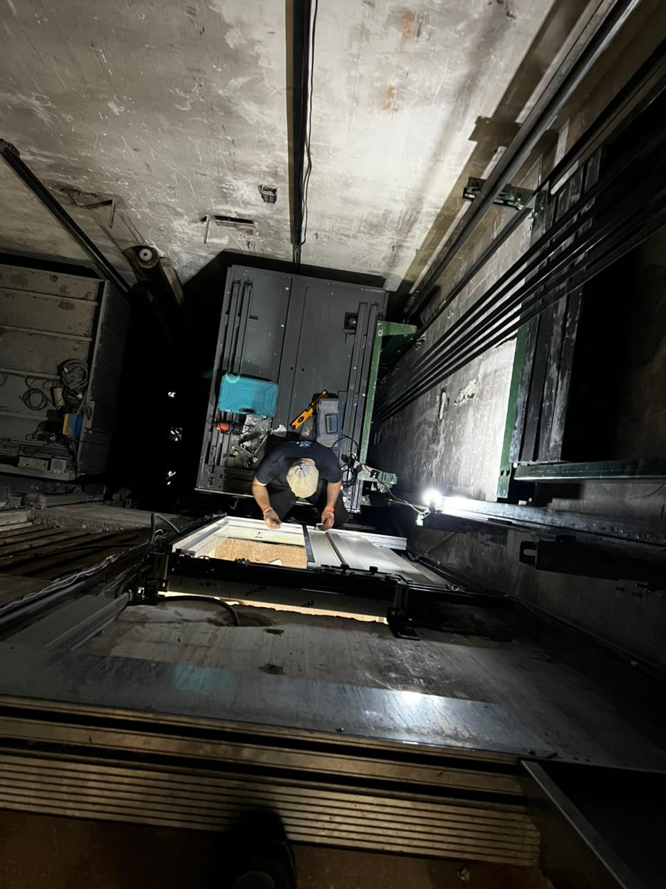 Técnico trabajando sobre la cabina dentro del hueco del ascensor